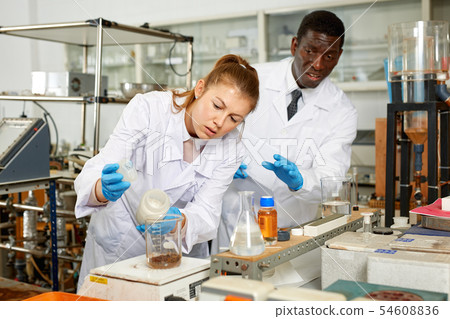 Focused lab technician woman with tubes and worried man technician Focused lab technician woman with tubes and worried man technician 54608836