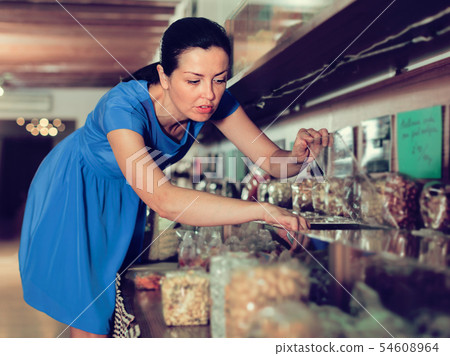Woman is taking nut beans by weight Woman is taking nut beans by weight 54608964