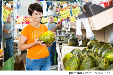 Female is choosing green melons 54609034