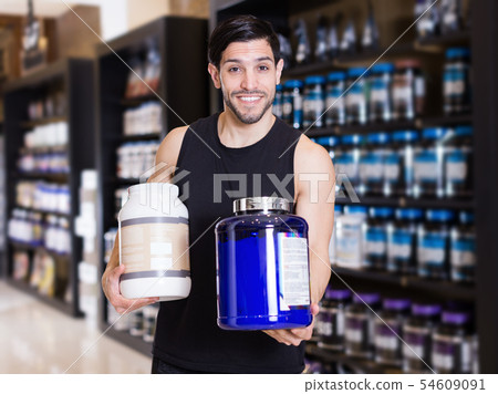 Young athletic man seller demonstration sport nutrition products 54609091