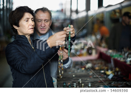 Mature couple looking antiques goods at flea market Mature couple looking antiques goods at flea market 54609398