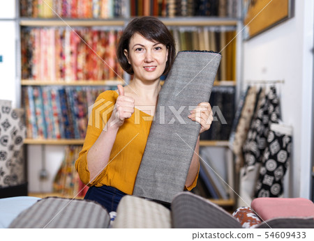 Woman giving thumbs up in fabric shop 54609433