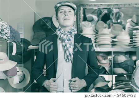 portrait of cheerful young male try on flat hat at the shopping mall portrait of cheerful young male try on flat hat at the shopping mall 54609458