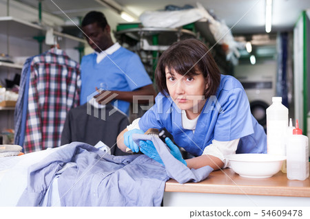 Woman dry cleaning clothes in laundry 54609478