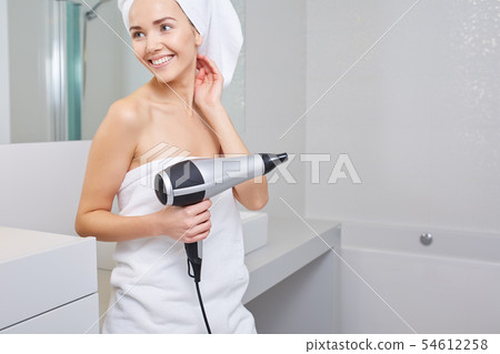 Woman in the bathroom with hairdryer in hand Woman in the bathroom with hairdryer in hand 54612258