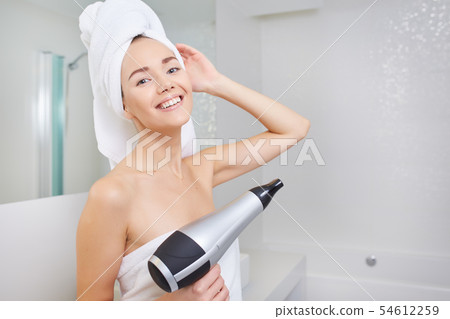Woman in the bathroom with hairdryer in hand Woman in the bathroom with hairdryer in hand 54612259