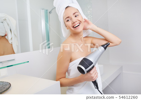 Woman in the bathroom with hairdryer in hand Woman in the bathroom with hairdryer in hand 54612260