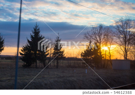Train window view with dramatic sunset light Train window view with dramatic sunset light 54612388