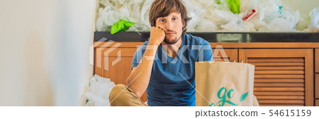 Man holding a package with the inscription GO GREEN amid a pile of plastic bags. Zero waste concept Man holding a package with the inscription GO GREEN amid a pile of plastic bags. Zero waste concept 54615159