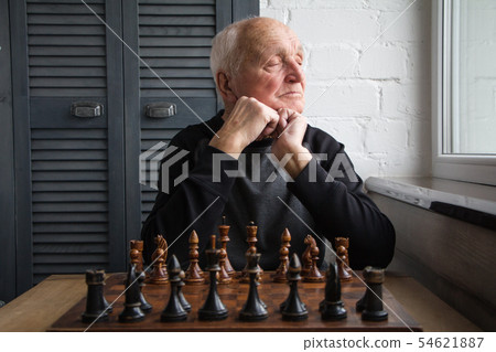 An old man sits in front of a chessboard, wonders An old man sits in front of a chessboard, wonders 54621887