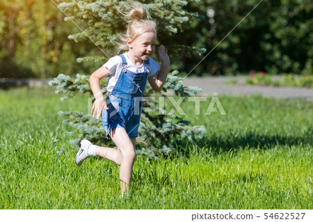 Children run on the green grass holding hands. 54622527