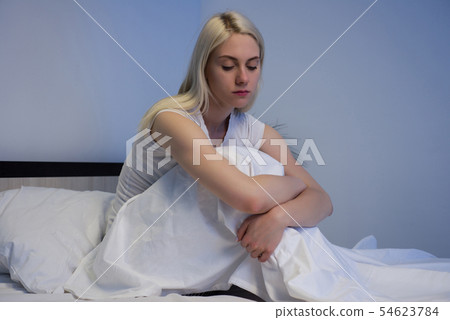 Sad depressed woman sitting in her bed late at 54623784