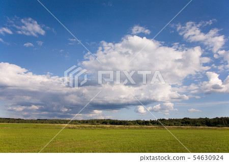 Cloudy sky and sun over cultivated meadows 54630924