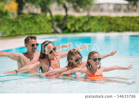 Happy family of four in outdoors swimming pool 54633786