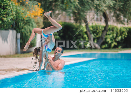 Happy family having fun together in outdoors swimming pool 54633903