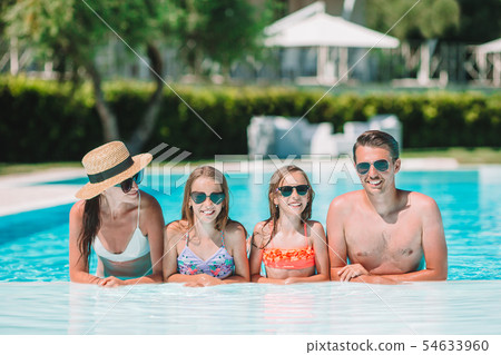 Happy family of four in outdoors swimming pool 54633960