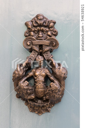 An old style decorative bronze door handle on a wooden door, the distinctive feature and symbol of An old style decorative bronze door handle on a wooden door, the distinctive feature and symbol of 54638921
