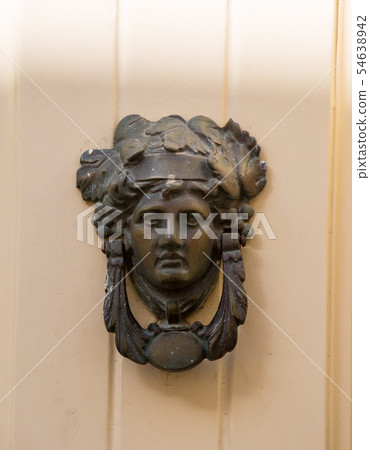 Decorative bronze traditional malttese door handle in the form of a beautiful woman's head on a red Decorative bronze traditional malttese door handle in the form of a beautiful woman's head on a red 54638942