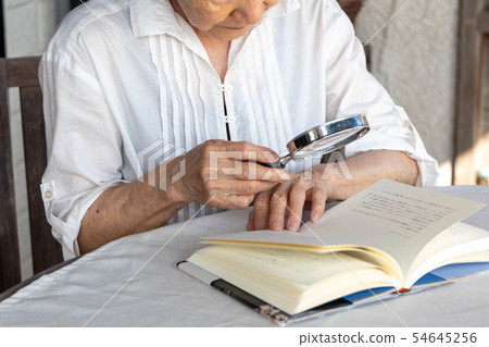 Senior reading with magnifier 54645256