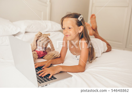 Cute little girl doing homework on laptop Cute little girl doing homework on laptop 54648862