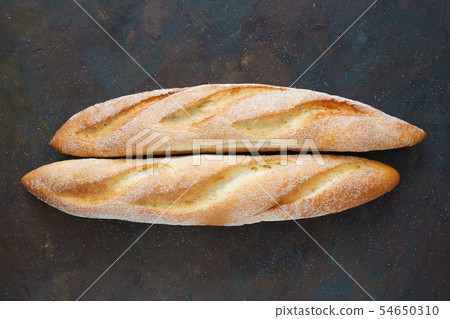 Two freshly baked baguettes on dark brown 54650310