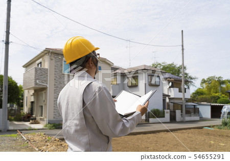 在站立在一個湧現的住宅區的盔甲的一個男性。 54655291