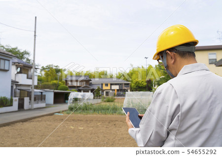 在站立在新興的住宅區發展站點發展領域調查片劑的盔甲的男性 54655292