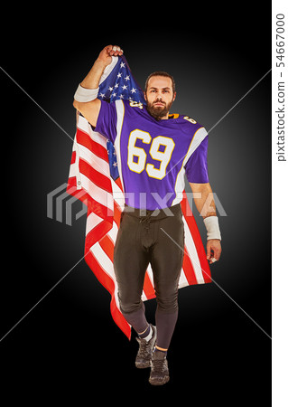 Patriotic american football player posing at camera on black background with usa flag. The concept Patriotic american football player posing at camera on black background with usa flag. The concept 54667000
