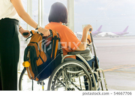 Woman with mother in wheelchair waiting for boarding at International airport. 54667706