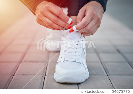 Female hands tying shoelaces on a sport sneakers 54675770