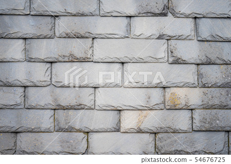 Part of an olf weathered slate tile roof as a background.Closeup detail pattern of grey stone tiles Part of an olf weathered slate tile roof as a background.Closeup detail pattern of grey stone tiles 54676725