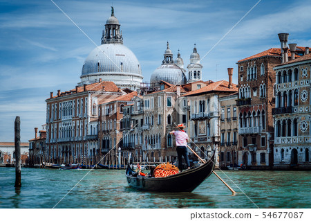 Traditional Gondola and gondolier on Canal Grande with Basilica di Santa Maria della Salute in the Traditional Gondola and gondolier on Canal Grande with Basilica di Santa Maria della Salute in the 54677087