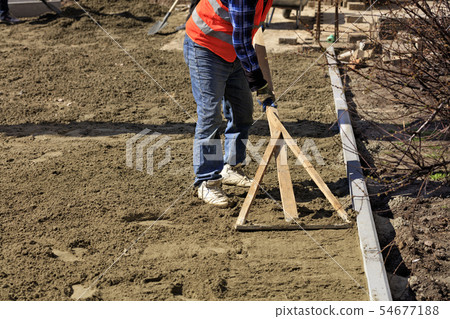 The worker aligns the foundation with a wooden 54677188