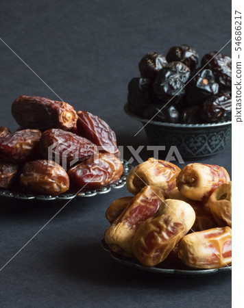 Saudi dates fruits are laid out on a dark table. Saudi dates fruits are laid out on a dark table. 54686217