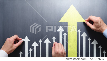 Leadership at work and the image of development and growth. Three male hands drawing an arrow on a blackboard. 54687637
