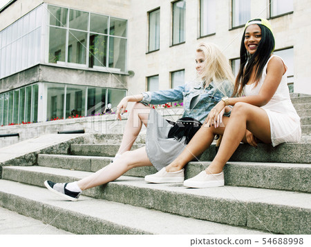 Two teenage girls infront of university building smiling, having fun traveling europe, lifestyle Two teenage girls infront of university building smiling, having fun traveling europe, lifestyle 54688998