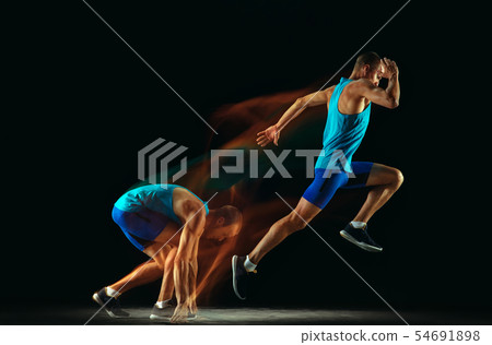 Professional male runner training isolated on black studio background in mixed light 54691898