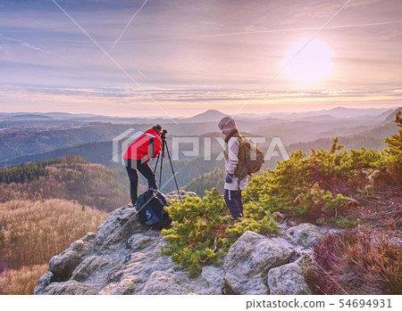 Two people stay at  tripod on background of a 54694931