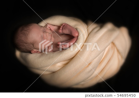 newborn baby sleeps wrapped in a white blanket 54695450