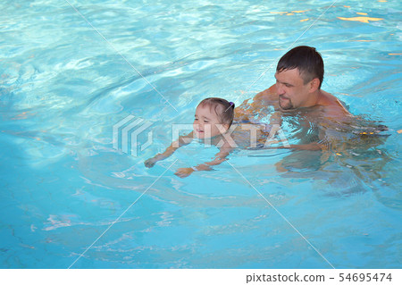 a man with a child swimming in the pool 54695474