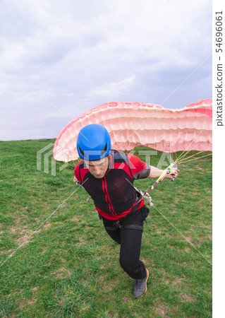 Landed young male skydiver paraglider extinguishes Landed young male skydiver paraglider extinguishes 54696061
