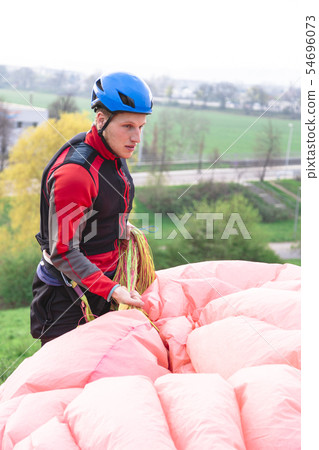 Paraglider landed after jump and raises parachute 54696073