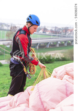 Landed young male paraglider raises parachute from Landed young male paraglider raises parachute from 54696074