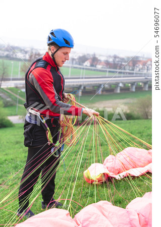 Landed young male paraglider raises parachute from Landed young male paraglider raises parachute from 54696077