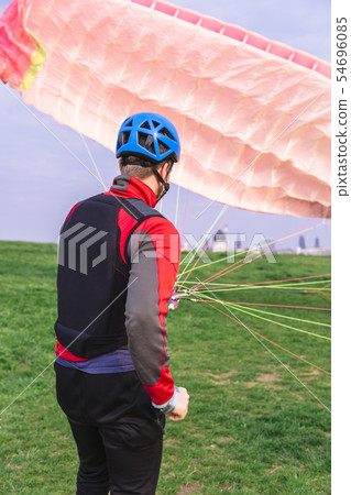 Paraglider landed after jump and raises parachute Paraglider landed after jump and raises parachute 54696085