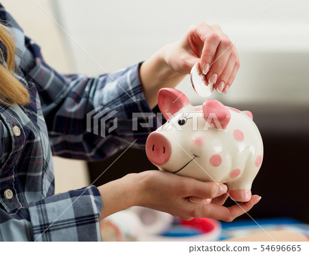 Female hand holding funny piggybank putting silver btc coin inside Female hand holding funny piggybank putting silver btc coin inside 54696665