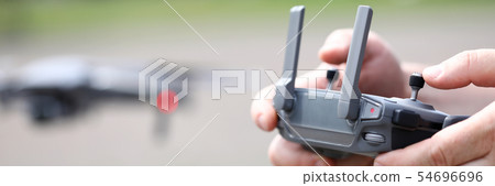 Modern video recording drone controlled with male hands holding remote controller Modern video recording drone controlled with male hands holding remote controller 54696696