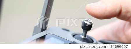 Male hand holding modern flying drone remote navigating it with stick 54696697