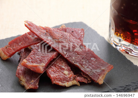 板岩板上的小吃，牛肉乾。在後面是一個可樂高的杯子。 54696947