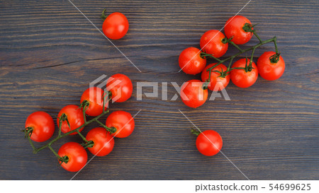 Ripe cherry tomatoes on a twig on a dark woden 54699625